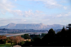 Der Flughafen wurde aus Platzmangel zum Teil knstlich ins Meer gebaut. Im Hintergrund  der  Pantokrator, der hchste Berg auf der griechischen Insel Korfu. Er befindet sich im Nordosten der Insel. Seine Hhenangaben schwanken zwischen 906 und 917 m.
